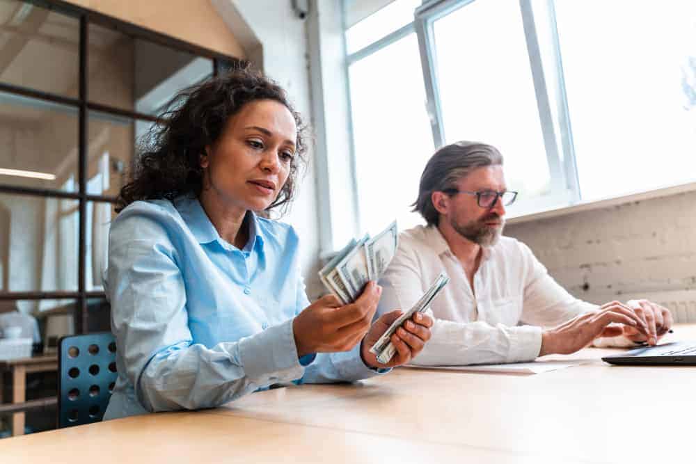 man woman counting bills bank office